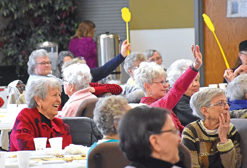 Seniors gathered around a table laughing and answering questions during a lively Jeopardy-style trivia game at Senior Day KC.
